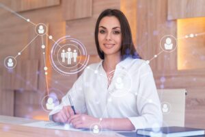 A imagem mostra uma mulher sentada em frente a uma mesa e diversos gráficos representando a conexão entre pessoas.